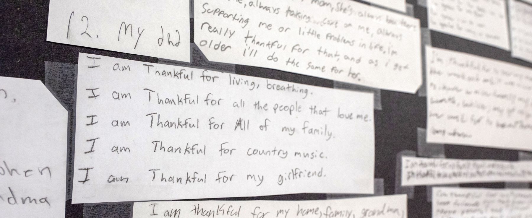 A wall filled with colorful notes and messages listing the things students are thankful for including family.