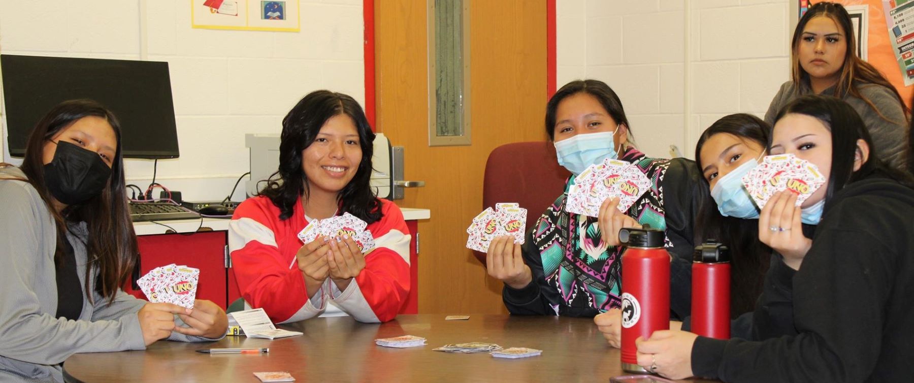 Female students sitting at table playing cards.