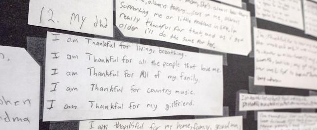 A wall filled with colorful notes and messages listing the things students are thankful for including family.